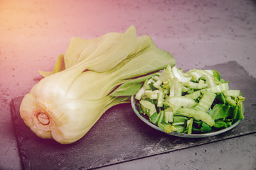 Sliced and whole pak choi cabbage on a stone countertop. Top view of vegetables. Concept of eating vegetables, using vegetables for dishes. Dish for a vegetarian. Healthy nutrition, vitamins.