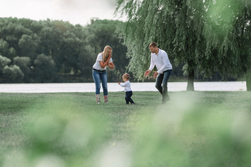 happy parents with their little son walking together in spring Park