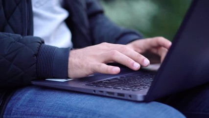 Close-up View of Man Using Laptop in the city street with bokeh effect