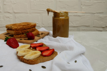 Nut-free vegan toasts with pumpkin seed butter, banana, strawberries on neutral background.