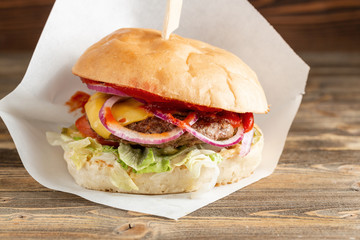 Burger with beef cooked on charcoal. Lunch on a wooden background. The concept of fast food and unhealthy food