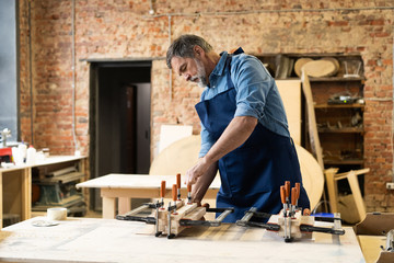 Mature handsome joiner work in carpentry. He is successful entrepreneur at his workplace.