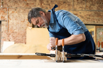 Mature handsome joiner work in carpentry. He is successful entrepreneur at his workplace.