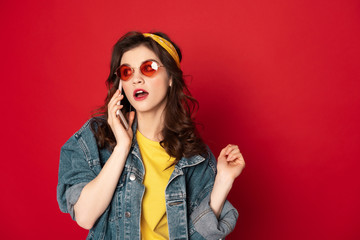 Surprised hipster girl talking by mobile phone