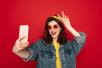 Naklejka premium Happy hipster girl making selfie on mobile phone