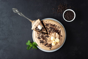 Fototapeta premium Tasty cake decorated with cream and dark chocolate on black background. Top view with copy space.