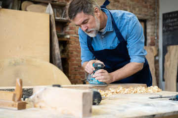 Mature handsome joiner work in carpentry. He is successful entrepreneur at his workplace.