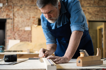 Mature handsome joiner work in carpentry. He is successful entrepreneur at his workplace.