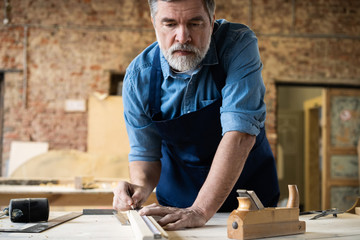 Mature handsome joiner work in carpentry. He is successful entrepreneur at his workplace.