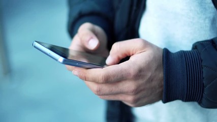 Close-up View of Man Using Smartphone in the city street.