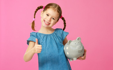 financial concept of children's pocket money. child girl with piggy Bank      on a colored pink background