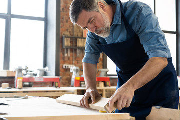 Mature handsome joiner work in carpentry. He is successful entrepreneur at his workplace.