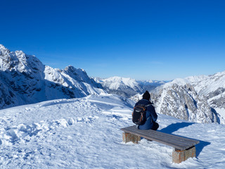 Persona con gorro negro,  sentada mirando el paisaje nevado de las montañas del Nordkette en...