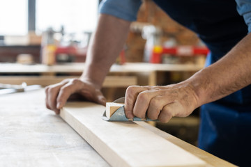 Carpenter working on woodworking machines in carpentry shop. A man works in a carpentry shop.
