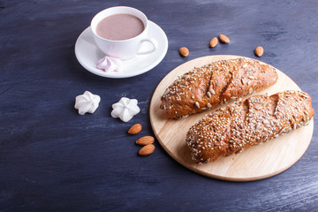 Rye bread with sunflower seeds, sesame and flax with cup of cocoa on dark blue background.