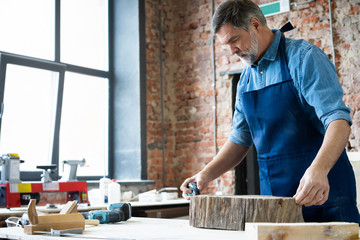 Mature handsome joiner work in carpentry. He is successful entrepreneur at his workplace.