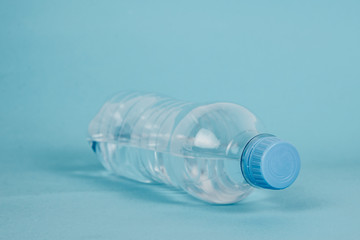 Plastic bottle with water on a blue background. The concept of thirst, the desire to drink clean water. Taking care of health, proper hydration of the body.