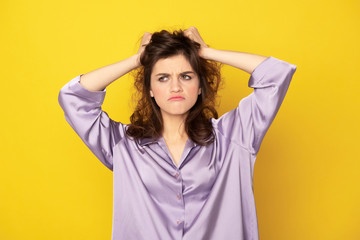 Annoyed young girl in pajamas grasping her hairs