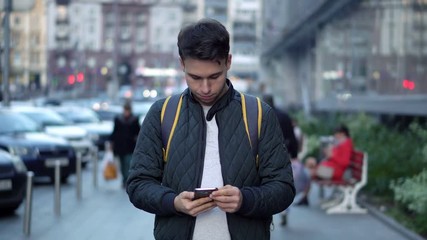 Young Attractive Man Typing Message Using Smartphone in the city street
