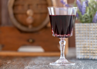 A glass of red wine and a bouquet of lavender flowers next to a wine wooden barrel. Art photography. Closeup. Soft focus.Toned image doesn’t in focus.