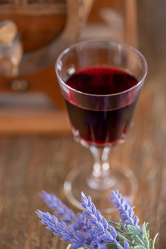 A glass of red wine and a bouquet of lavender flowers next to a wine wooden barrel. Art photography. Closeup. Soft focus.Toned image doesn’t in focus.