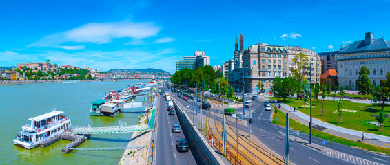 Panoramic cityscape view of hungarian capital city of Budapest from Elisabeth Bridge. The quay of river Danube. Summertime sunshine day, blue sky and green of trees.