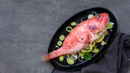 raw fresh ocean perch, ready to cook, olive oil, lemon, on the grey stone backgropund