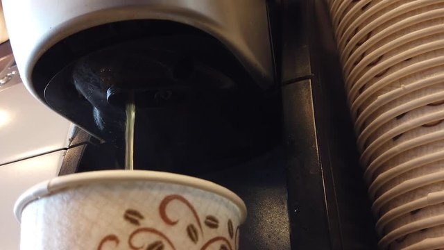 Close up view of automatic coffee machine dispensing a stream of coffee into a Styrofoam cup