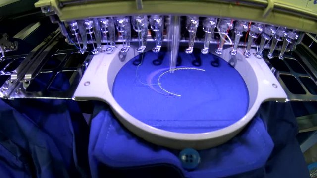 Running Embroidery machine with embroidery logo at T-shirt in Garment Textile Manufacture Industry