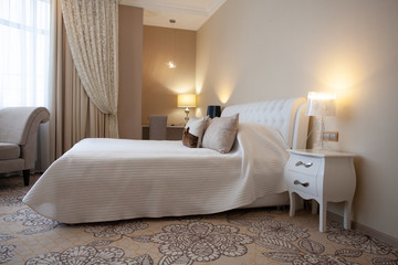 Luxury design interior of hotel room in soft brown and beige color tone. Peace and quiet. Sweet home. King size bed in the middle of the room.