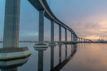 The massive Jordan Bridge over the Elizabeth River in Virginia, reflecting in the water at sunset,...