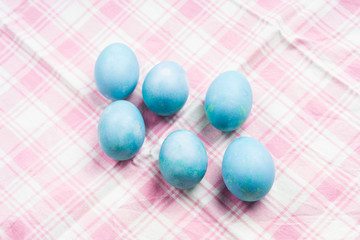 Blue pastel easter eggs on pink table cloth. Festive flat lay