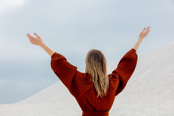 Girl in burgundy color blouse on a white sand brach.