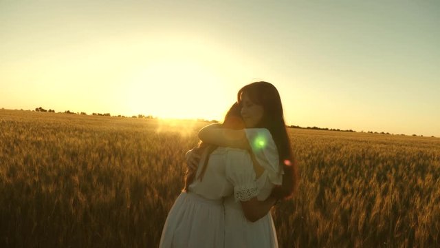 adult daughter in arms of her mother in field in the rays of the sun. mom strokes her daughter's hair. Mom gently hugs daughter against backdrop of a beautiful sunset. happy family concept.