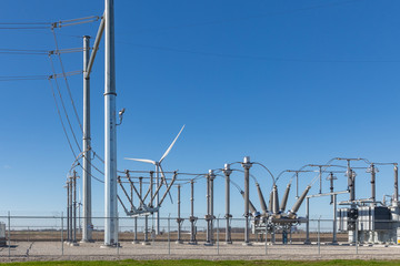 electrical substation with a wind turbine in background supplying the power