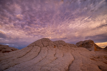 White Pocket Utah, the strange petrified geological rock formations contrast the unique, vibrant sunset in this protected, deserted sandy location in the desert area bordering Arizona