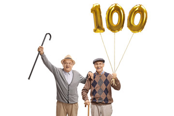 Happy senior men with a golden number hundred balloon