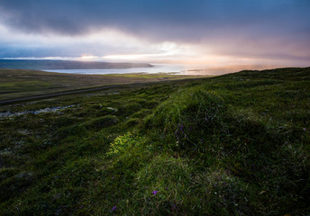 Soft, somber vibrant clouds blanket the lush green landscape of Iceland.  This beautiful capture during soft light encompasses the Scandinavian culture and Nordic weather in an artistic way.