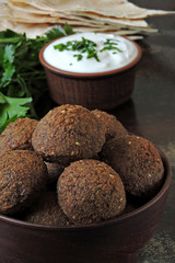 Fresh homemade falafel in a bowl with sauce, parsley and pita. Middle Eastern cuisine.