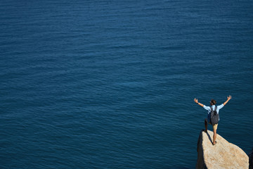 Traveler posing on stone on rocky seashore outdoors