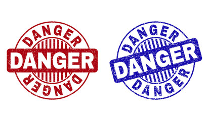 Grunge DANGER round stamp seals isolated on a white background. Round seals with grunge texture in red and blue colors. Vector rubber imprint of DANGER label inside circle form with stripes.