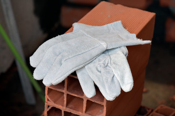 Pair of protective gloves on pile of red bricks