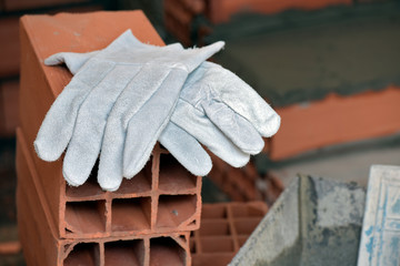 Pair of protective gloves on pile of red bricks