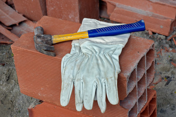 Protective gloves and hammer on pile of bricks