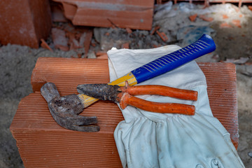 Protective gloves and masonry tools on pile of bricks