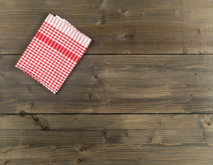 Red checkered dishcloth on brown rustic wooden plank table flat lay top view from above