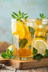 Traditional iced tea with lemon and ice in tall glasses on a wooden rustic table. With copy space