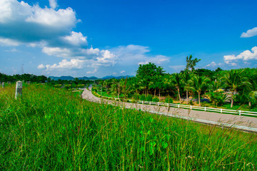 Fototapeta na wymiar street view with green mountain on blue sky background in the province of Thailand. decoration image contain certain grain noise and soft focus.