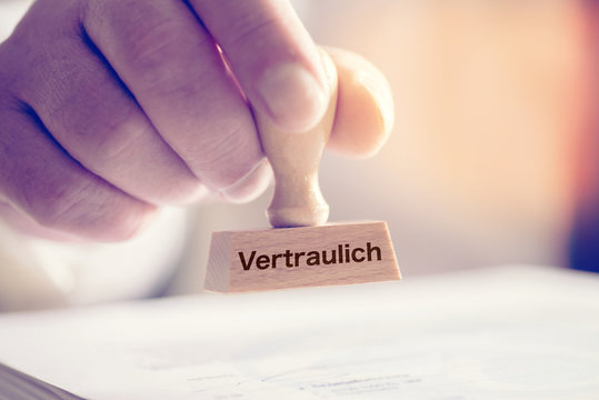 Ein Mann und ein Stempel mit dem Aufdruck Vertraulich