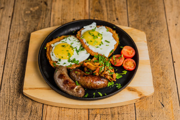 Naklejka na ściany i meble Traditional potato pancakes with fried eggs, mushrooms, sausages and tomatoes served on a hot frying pan.